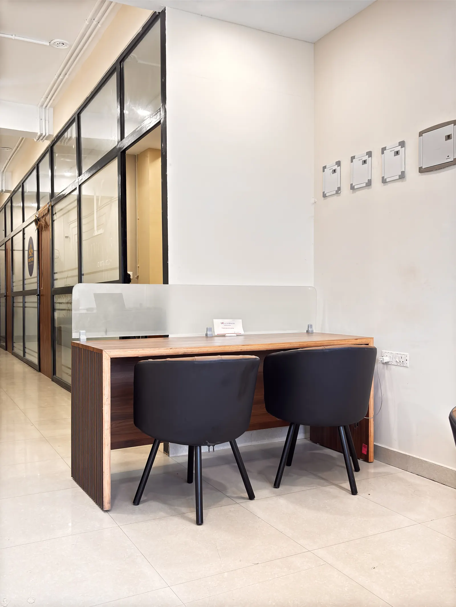 Two-seat coworking desk with a frosted glass divider and a wall socket for charging