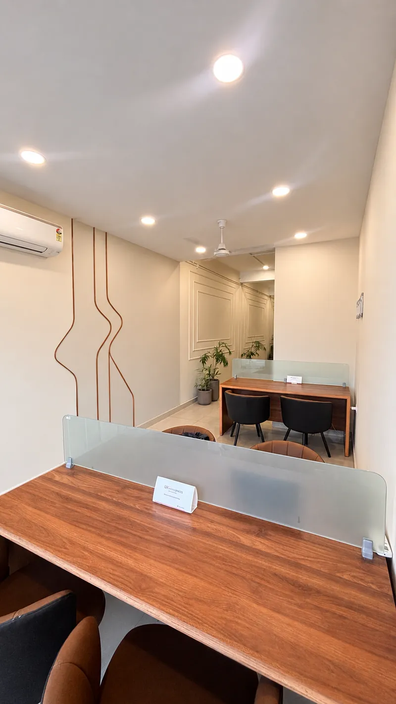Air-conditioned coworking hall with a copper wall inlay, walnut desks and indoor palms